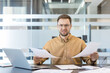 © Liubomir - Workplace stress and burnout, frustrated businessman reviewing documents at office desk with laptop. Professional man analyzing paperwork and feeling pressure during a busy workday in a modern office.