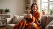 © MyDigitalCraft - person wrapped in blanket on sofa, Young woman relaxing on sofa with warm drink and orange blanket at home