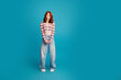 © deagreez - Young redhead woman standing in casual striped crop top and wide-leg jeans on turquoise background, playful surprised expression, fashion portrait and lifestyle concept