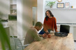 © Wavebreak Media - Couple sitting at wooden table in kitchen, checking smartphone beside turntable and mug, copy space