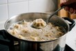 © Vadym - Person lifts spoon with boiling dumpling from pot of water. Many stuffed dough parcels cook in bubbling liquid. Preparing tasty home cooked meal.