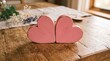 © Mark Hoppus - Two pink wooden hearts sitting on a rustic wooden table as a romantic symbol for love and Valentine's Day decoration