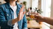 © Novi - Sobriety Concept Showing a Woman Refusing a Glass of Whiskey with a Clear Gesture of Rejection in a Social Setting