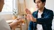 © Novi - Sobriety Concept with a Young Man Declining a Glass of Whiskey or Alcohol in a Social Setting