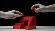 © Asghar - Teamwork concept with hands connecting red puzzle pieces to build a structure representing cooperation and problem solving