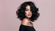 © Fun Factory - Portrait beautiful young woman with voluminous long black wavy hair, lipstick lips posing elegantly against soft pastel pink studio background, wearing makeup and stylish black bare shoulders top