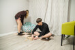 © dizfoto1973 - Young Teenagers Playing Wooden Tower Block Game Sitting on Floor at Home