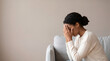 © Kaluya Stock - Sad young woman covering face with hands crying while sitting on sofa at home