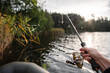 © Serhii - Angler fishing with a spinning rod from an inflatable boat near the reeds on a calm lake, catching fish during a sunny afternoon outdoors.