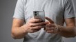 © Gophotograph - A young man holding a smartphone in a studio with a gray background.