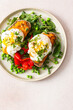 © pundapanda - Plates of gluten free bread sandwiches filled with zucchini caviar and topped with poached eggs. Served with roasted red peppers, green peas, and spinach for breakfast