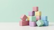© Raphael - Pastel Building Blocks: A charming arrangement of pastel-colored building blocks stacked in a playful pyramid against a soft mint-green backdrop, evoking a sense of creativity and childhood wonder.
