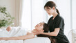 © pattozher - Relaxing Massage Session: A woman receives a therapeutic neck massage from a professional therapist in a tranquil spa environment, promoting relaxation and well-being.