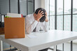 © Charlie's - Asian Businessman Touching Forehead with Headache at Office Desk Experiencing Burnout Stress and Emotional Pain from Boring Job.