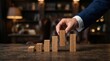 © Chayanan - A professional hand placing wooden blocks to represent strategic portfolio restructuring and growth.