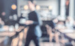 © dwi - A blurred view of a busy café with patrons seated at tables. A waiter carries a tray, creating a lively atmosphere of dining and social interaction.