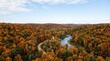© Elenba - Autumn landscape view with colorful forest trees and winding river. Autumn landscape panorama includes vibrant orange foliage, serene blue water and narrow road. Peaceful Autumn landscape for travel.