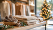© Olha Havelia - Bright clean boutique display with clothing and frosted pinecones and holly sprigs along shelf edge soft natural light neatly arranged garments on rack festive Christmas retail con
