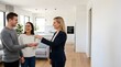 © Emily - Real estate agent handing house keys to a happy couple in a new home
