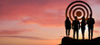 © New Africa - Silhouettes of employees and target against sunset sky, banner design. Teamwork concept