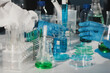 © Aungkana - Female and Male Scientists Working on their Computers In Big Modern Laboratory. Various Shelves with Beakers, Chemicals and Different Technical Equipment is Visible.