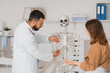 © Pixel-Shot - Male doctor showing rib cage of human skeleton model to female patient in clinic