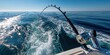 © The Little Hut - Deep Sea Fishing Rod Bent Over Ocean Water with Boat Wake and Clear Blue Sky