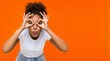 © wirbron - Funny young black woman looking through hand glasses on orange