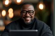 © njna - Middle-aged african american businessman smiling broadly with glasses in an office setting