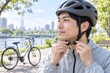 © sakura - サイクリング前に自転車ヘルメットのあご紐を留める男性
