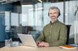 © Liubomir - Customer support and remote work, smiling businessman with headset using laptop at office desk for professional communication and business analysis. Expert employee working on data documents.