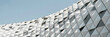 © Background - Geometric architectural facade featuring a repeating pattern of white triangular panels and metallic edges against a clear blue sky