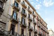 © daily_creativity - Historic Liberty style apartment building with ornate balconies and stone decorations seen from below against a blue sky with white clouds, low angle view of an elegant European facade in summer, con