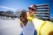 © CarlosBarquero - Happy couple share a fun piggyback pose outdoors in a sunny residential district, creating a lively lifestyle and relationship portrait.