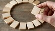 © Generative AI - Hand placing wooden dominoes in circular pattern