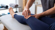 © RAAL - Professional physiotherapist examining and massaging a patient knee joint in clinic
