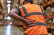 © Generative AI - Warehouse worker holding lower back in pain after