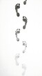 © SAKANDI  - Wet human footprints walking forward on a white surface, fading gradually