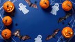 © rahwik - overhead flat lay of sophisticated halloween decor including glowing jack o lantern ghosts and silk bats on royal blue backdrop for commercial poster mockup