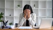 © Chandlerlikes - Sad female employee covering face with hands while sitting stressed at busy modern office desk