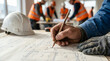 © Djenggo - Construction worker sketching blueprint, team planning at site