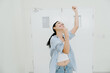 © JK_kyoto - Joyful woman celebrating success with excitement and happy expression in casual clothing inside bright white modern building room