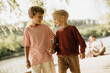 © BGStock72 - Two young boys joyfully walking hand in hand by the lakeside during a sunny day