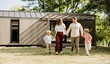 © BGStock72 - Joyful family stroll in a sunny backyard near their modern home
