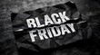 © MD.RAKIB MIA - Black friday text printed on a torn piece of black crumpled paper on a dark wooden surface