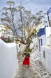 © Mara Brandl/imageBROKER - Young woman with red skirt in the alleys of the old town Chora, Cycladic white houses with blue shutters, Mykonos Town, Mykonos, Cyclades, Greece