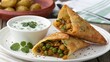 © Anna - Indian spicy vegetable samosa served with mint yogurt sauce on a plate