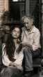 © SirArbusto - Generations Intertwined: An elderly woman gently braids the hair of a young woman, a tender moment of connection on a rustic porch, evoking a sense of heritage and love.