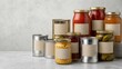 © Svetlana - Assorted canned and jarred preserved foods with blank kraft labels arranged on a neutral surface
