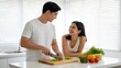 © LamMinh - Happy Asian Couple Cooking Fresh Vegetables Together in Bright Modern Kitchen